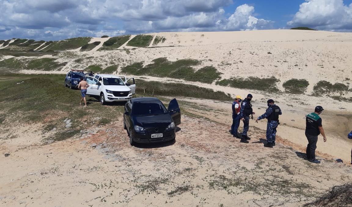 carros em duna e fiscais ao lado falando